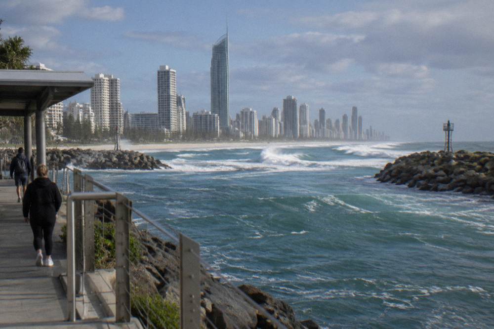 Waves breaking across a narrow coastal bar channel between two rock walls