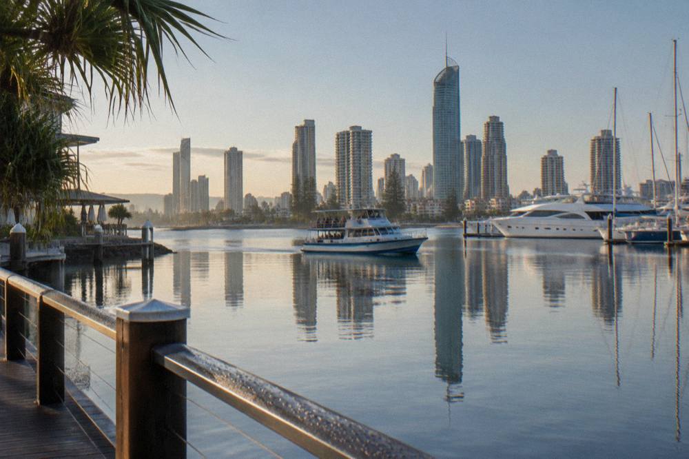 A whale watching boat on glassy calm water with the Gold Coast skyline behind it