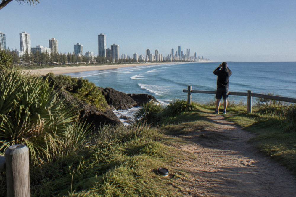 Grassy headland path above a long sandy beach