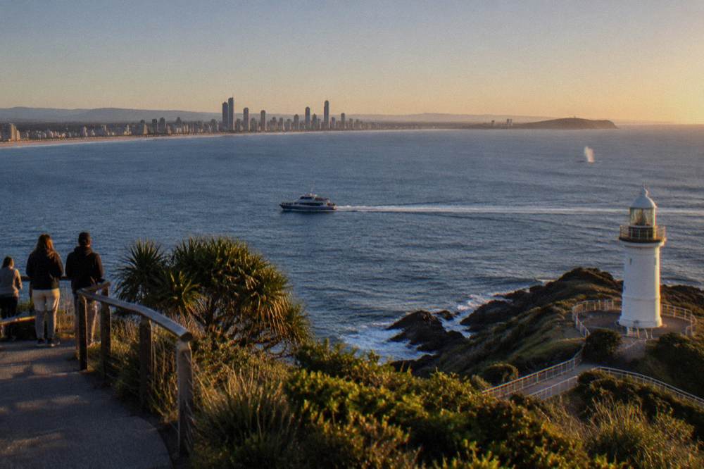 Whale watching boat cruising past a headland in early morning light