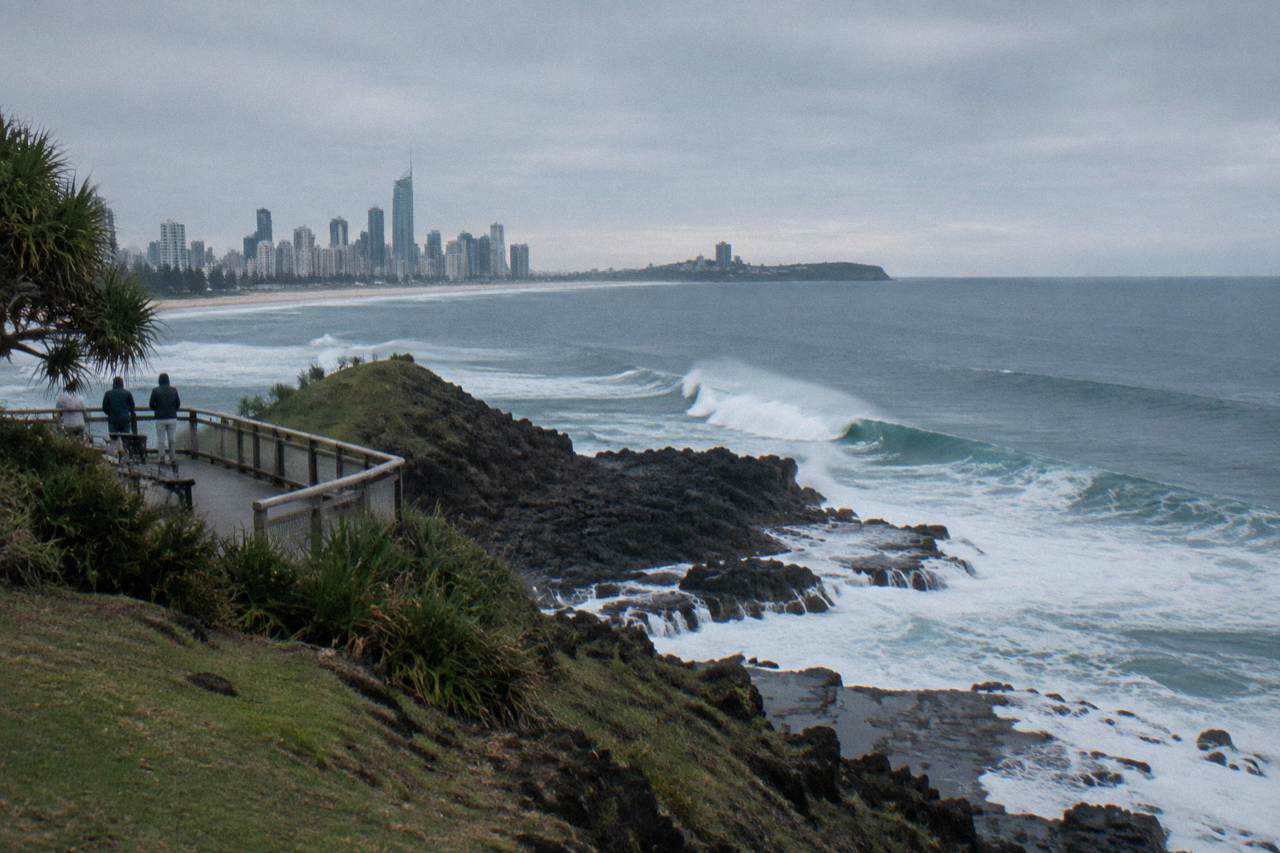 Open ocean swell rolling past a rocky Gold Coast headland under a pale winter sky