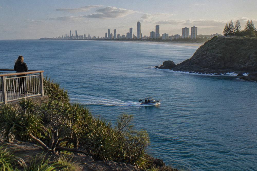 A small whale watching boat on calm blue water near a green headland