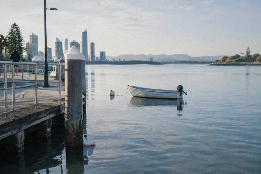 A calm sheltered bay with glassy water and distant wooded hills