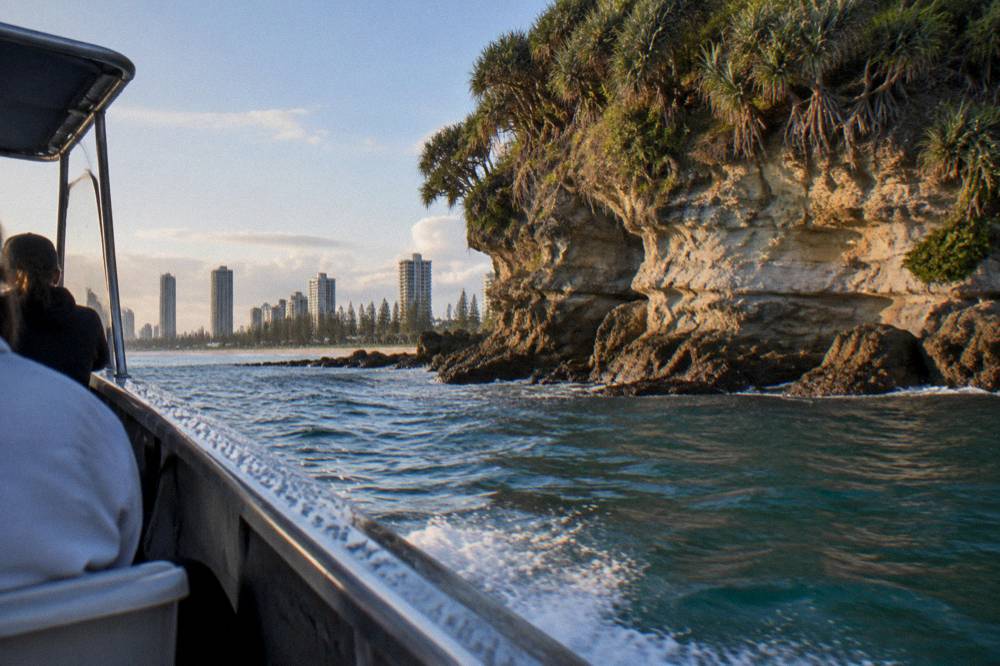 Small open safari-style boat cruising close to headland cliffs